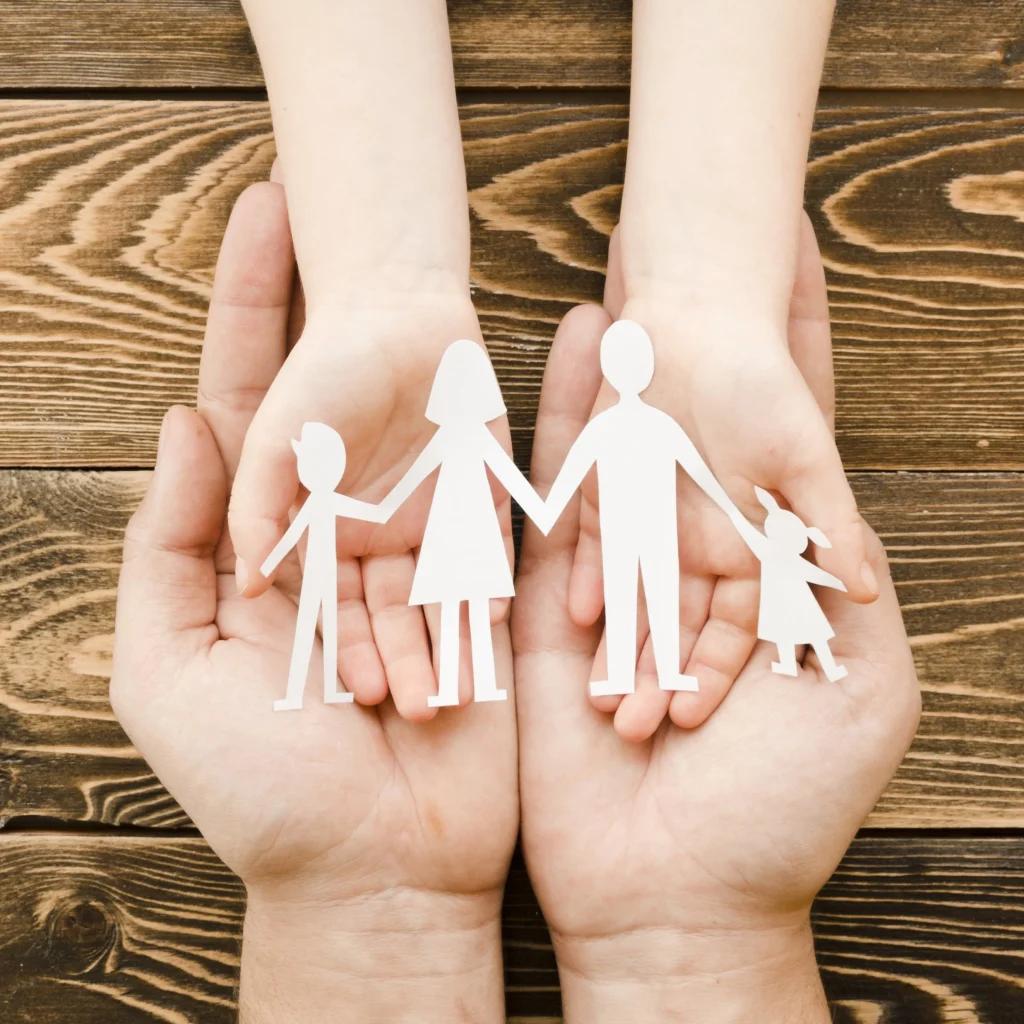 Parent holds child’s hands that are holding paper family. For difficult legal family matters, contact our Katy family lawyers.
