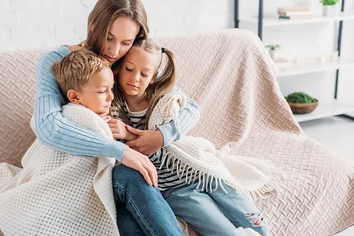 Woman cuddles with her two children.
