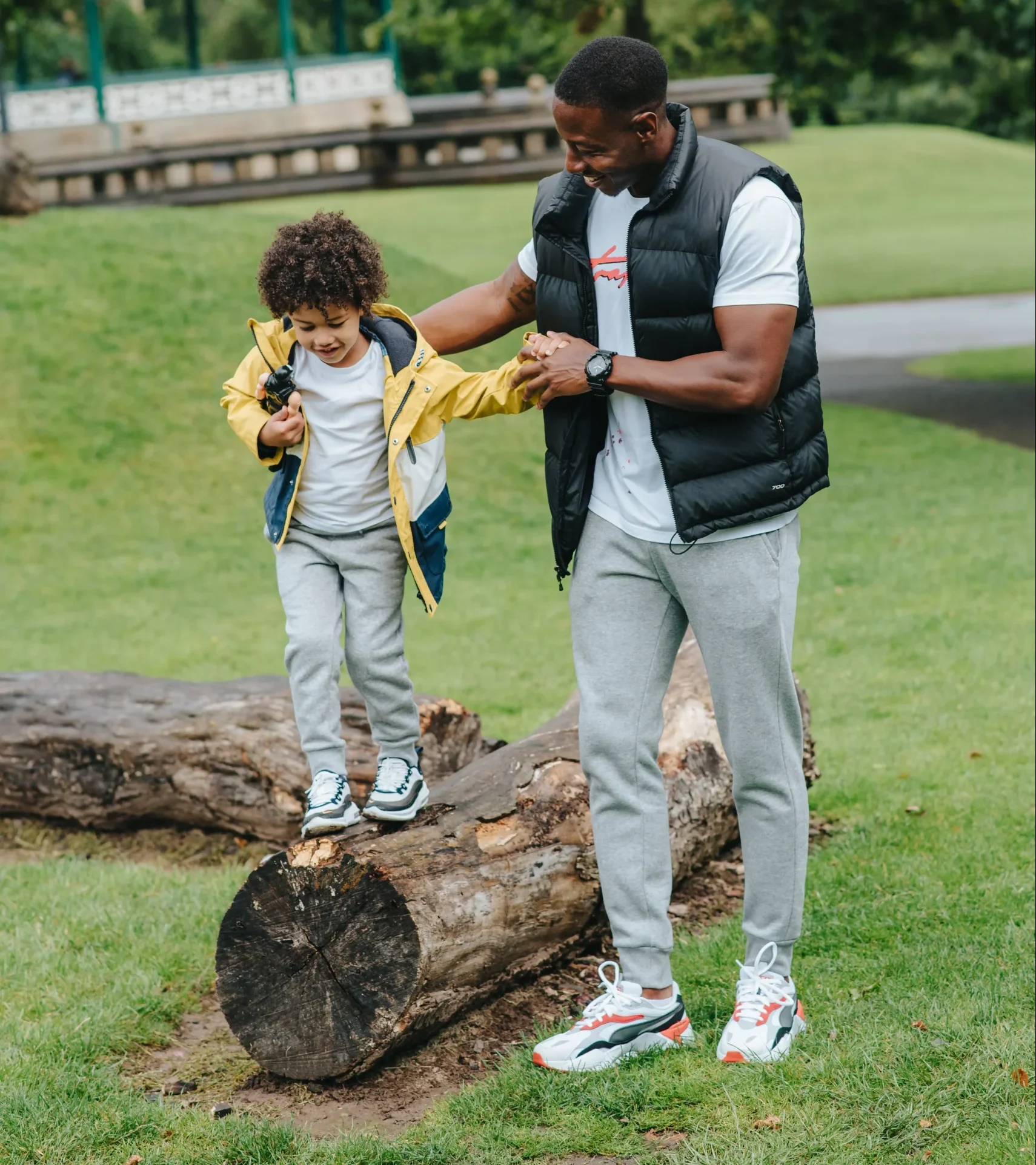 Father helping child walk across a log. 