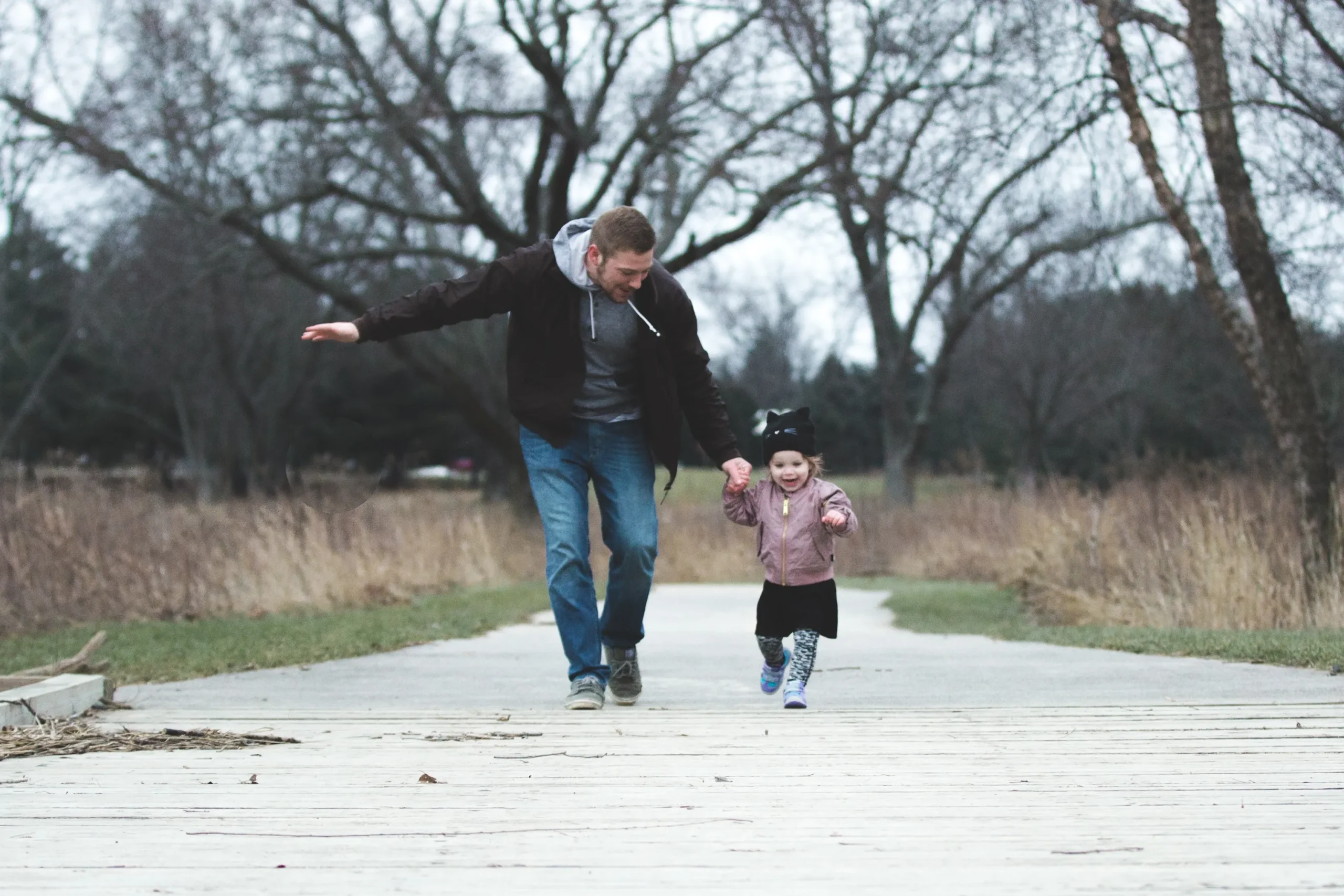 Father and child running on a path in the woods together. 
