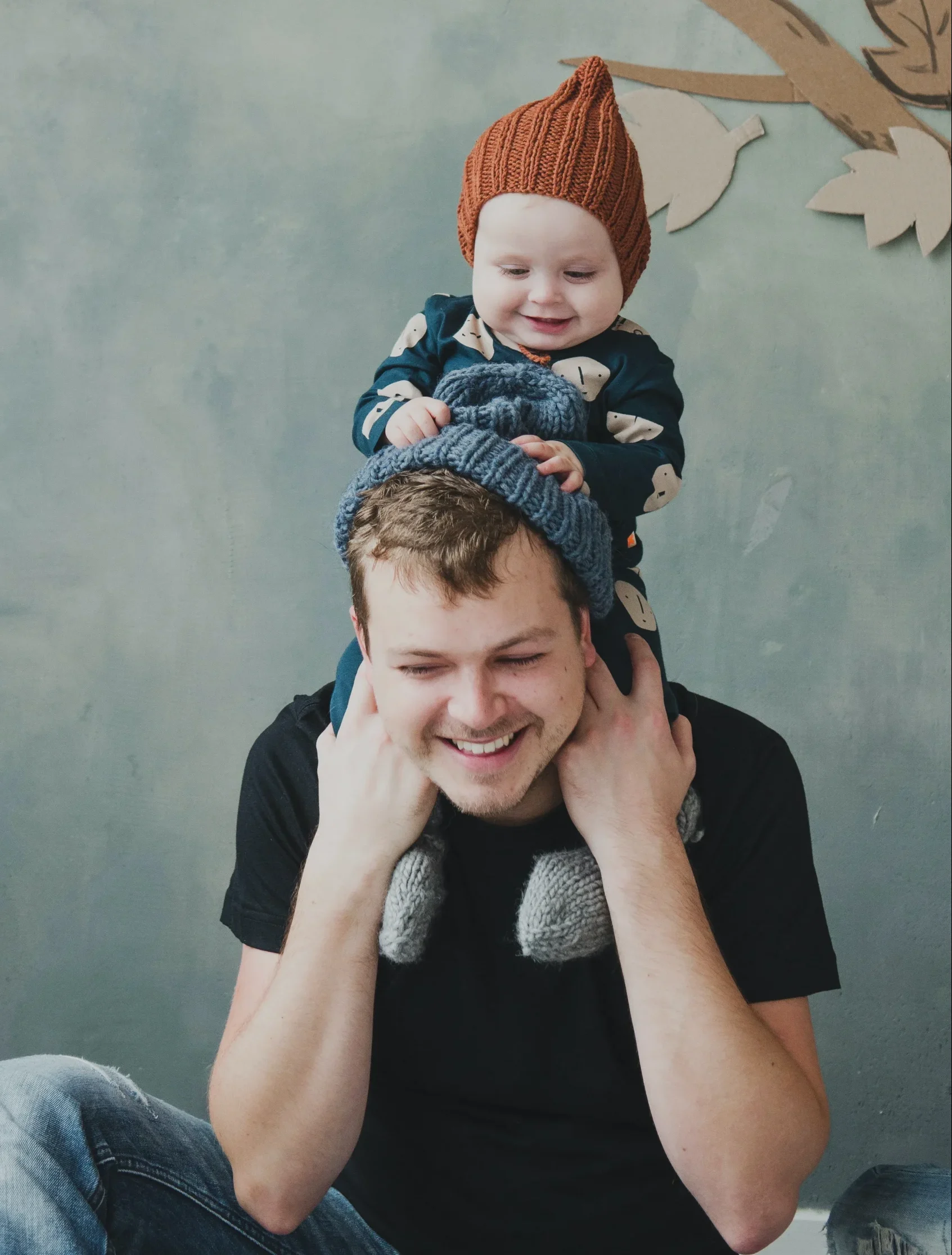 Father holding baby on his shoulders and smiling. 